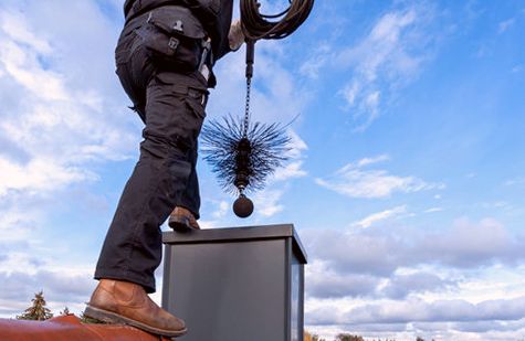 Technician atop a metal chase with a weighted flue brush