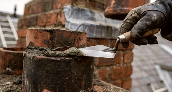 Trowel bedding mortar around a clay flue tile