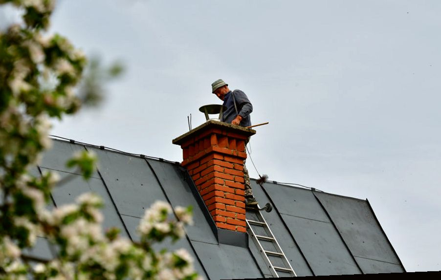 Chimney sweep working at a red brick chimney on an Old Bridge NJ roof in spring